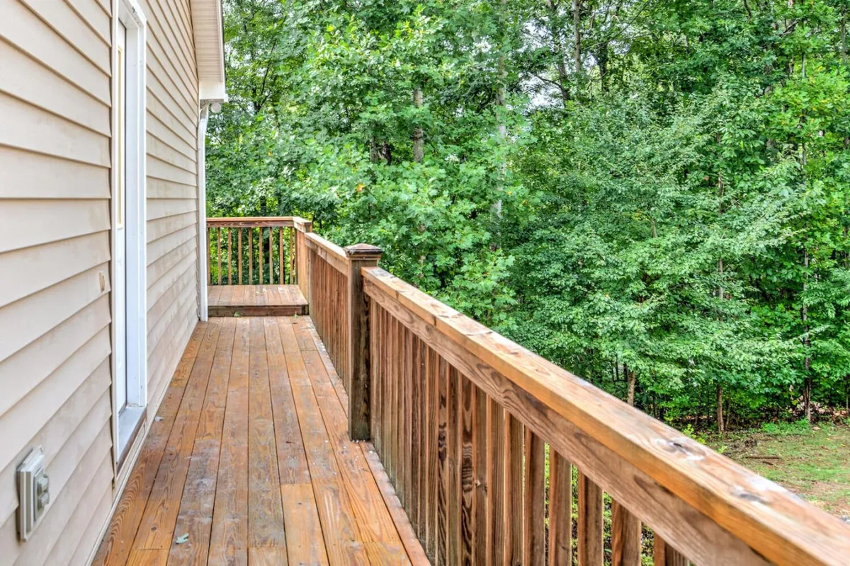 This image shows a serene wooden deck nestled among lush greenery. The deck looks inviting, with plenty of space for relaxing after outdoor adventures. The surrounding trees and natural landscape create a peaceful retreat, perfect for unwinding with your furry companion.