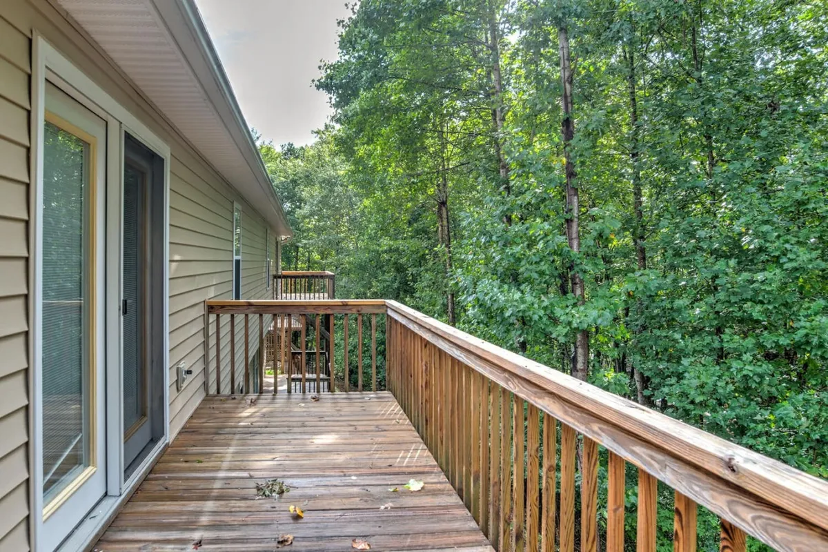 The image captures a tranquil wooden deck framed by tall trees and the exterior of the house. It evokes a sense of being immersed in nature, with space for outdoor relaxation, sunbathing, or simply enjoying the fresh mountain air—ideal for both people and their pets.